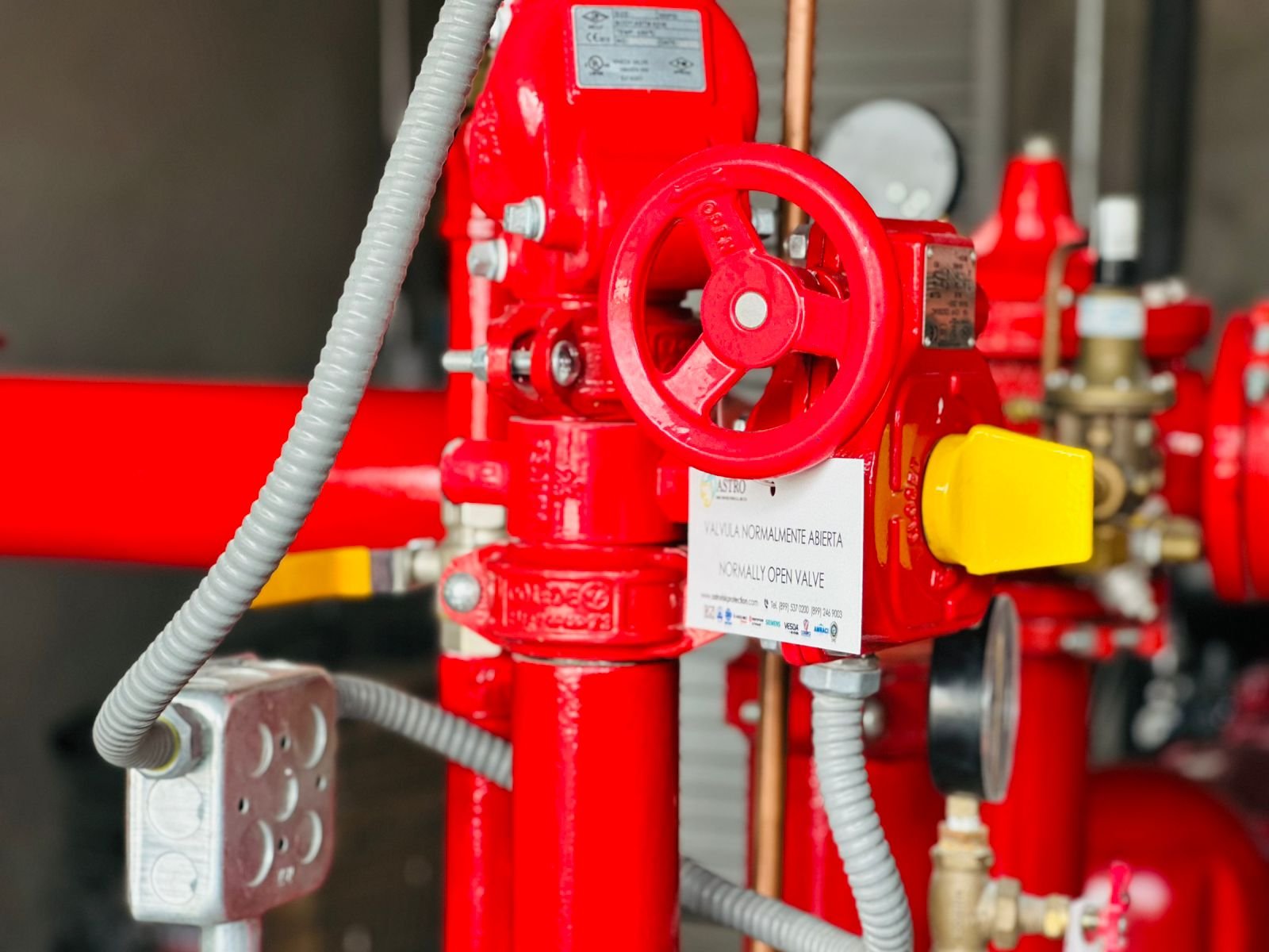 Detalle de una válvula roja con volante y tuberías del sistema contra incendio.